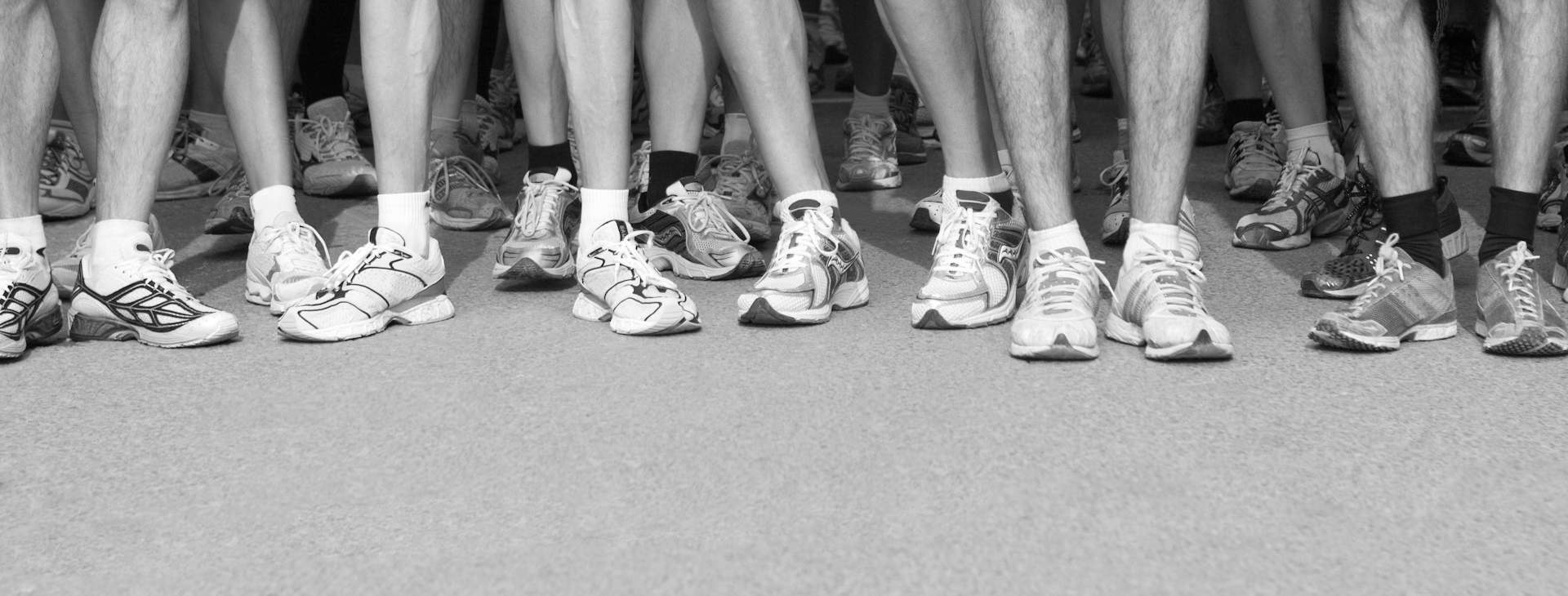 Runners at a start line, all in conventional cushioned running shoes